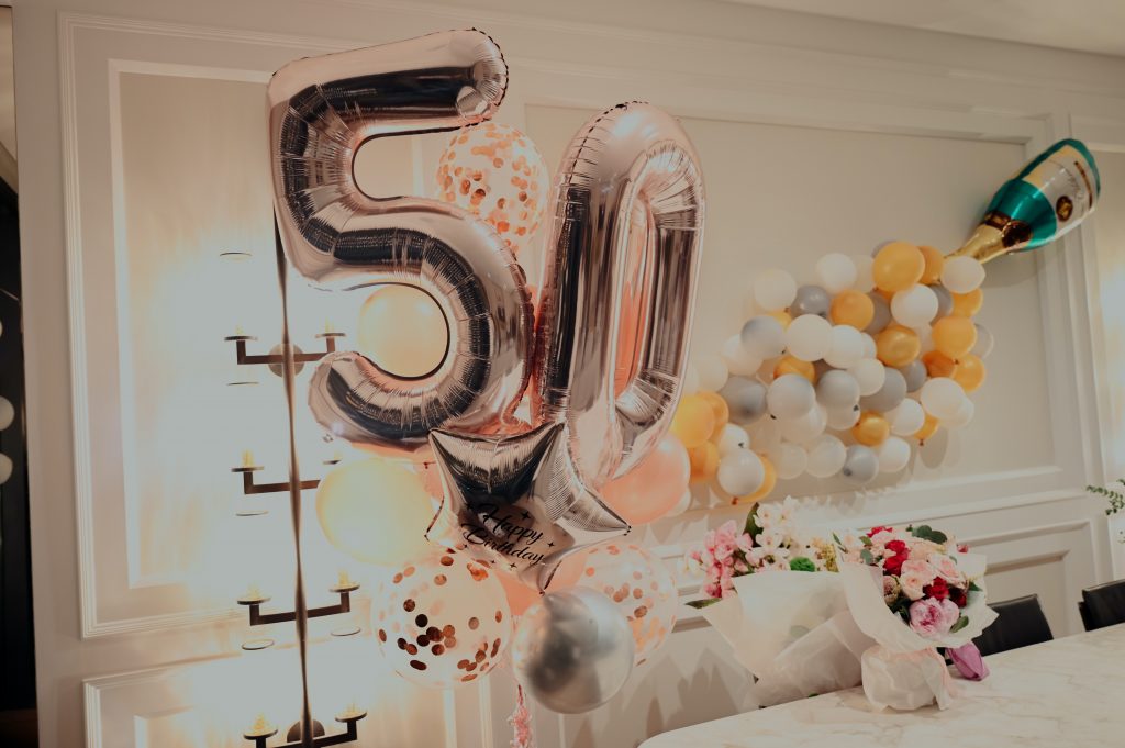 A birthday party table with balloons and flowers, with a large 50 decoration.
Photo by lucas law on Unsplash.